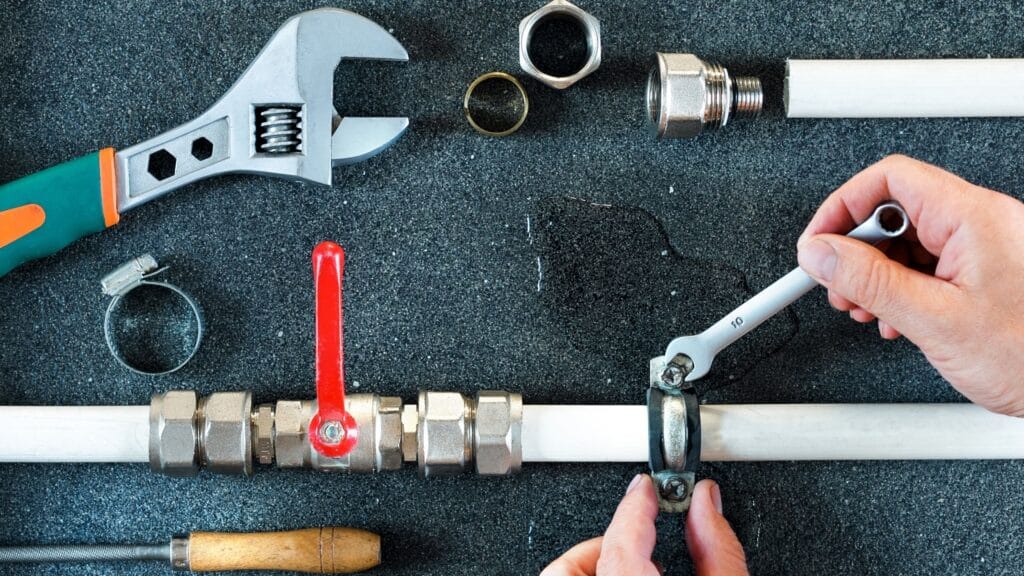 Plumber repairing a pipe valve with an adjustable wrench in Navarre