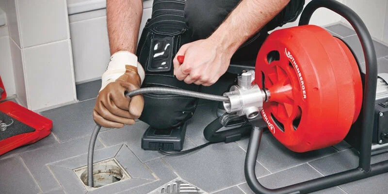 Plumber using a drain-cleaning machine in Navarre